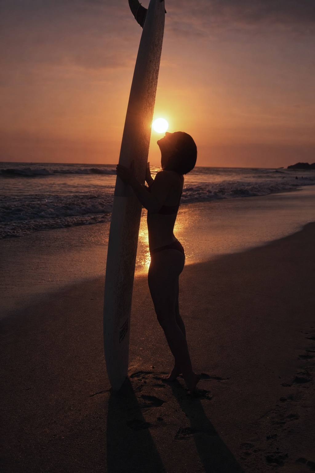 Alie with surfboard on a tropical beach